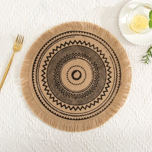 Macro detail of round jute placemat with black geometric pattern and fringed edges