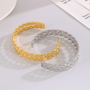 Detail of twisted woven open bangles in gold and silver finish on marble background
