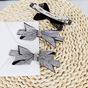 Close-up of three crystal rhinestone bow hair clips in black, silver, and rainbow colors