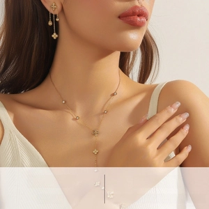 Close-up of gold clover pendant necklace and fringe earrings set with white crystals
