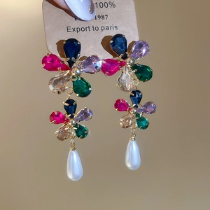 Detail of flower earrings featuring multi-color crystals and a drop white pearl pendant