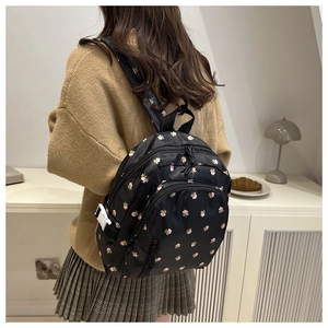 Back view of a floral crossbody backpack worn by a model in a cozy indoor setting