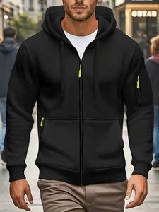 Close-up of black men's zip-up hoodie featuring a fluorescent green zipper pull detail
