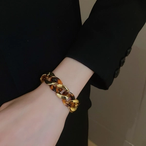 Detail of leopard print linked bracelet with gold metal chain worn on a model's wrist