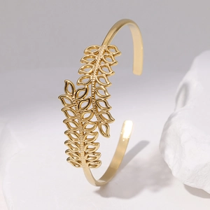 Detalle de brazalete de acero inoxidable con hojas huecas doradas en piedra