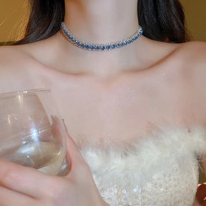 Detail einer funkelnden Halskette mit blauen Edelsteinen und klaren Kristallen am Model