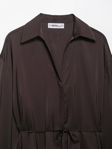 Detailed close-up of dark brown satin shirt collar with elegant V-neck and branded label