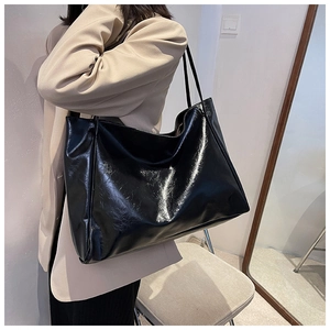 Detailed view of the shiny black leather tote bag showing vintage texture and large capacity