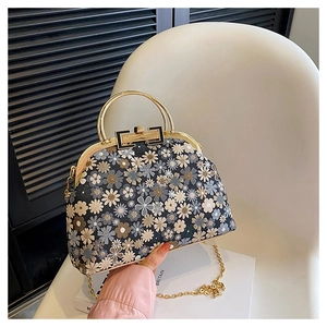 Detail of vintage floral embroidered shell bag with gold metal handle and chain strap