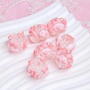 Close-up of pink round acrylic beads with embossed heart patterns for DIY jewelry making