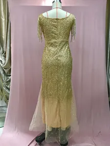 Dettaglio dell'abito da sera dorato con paillettes, spalle con frange e fondo a sirena