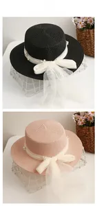 Detail of flat top straw hat with mesh bow and white pearl accents on iron basket