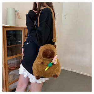Close-up of a brown plush capybara bag with a small pink flower detail on model