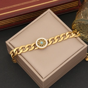 Detail of gold Cuban chain bracelet featuring a green stone centerpiece with crystal halo