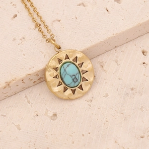 Detail of a vintage gold sunburst pendant with an oval turquoise stone and fine chain