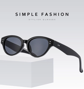 Detailed side view of black cat-eye sunglasses with silver dot metal accents on white stand