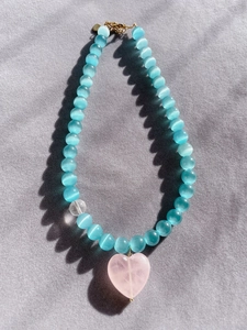 Detail of glacier blue cat eye beaded necklace with pink heart pendant and gold clasp