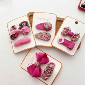 Detailed set of floral fabric bow hair clips and strawberry buttons on wood tray