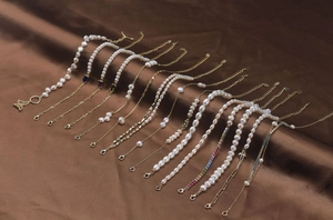 Détail de bracelets et colliers en perles baroques sur un tissu en soie marron