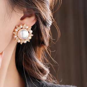 Macro shot of a floral pearl earring featuring crystals and a large central pearl