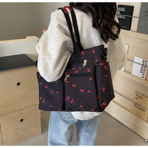Detail of black nylon tote bag with cherry print and multi-pocket functional design