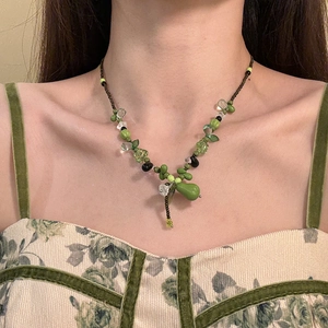 Gros plan d'un collier de perles vertes avec nœud et fleurs sur un mannequin