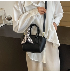 Detail of black lychee grain bucket bag featuring silk scarf handle and gold hardware