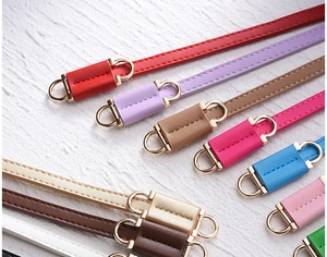 Detailed close-up of multiple colorful PU leather belts with gold double ring buckles