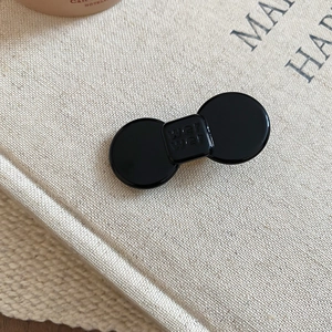 Close-up of black resin bow hair clip featuring a minimalist square wer wer letter engraving