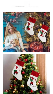 Detail showing a white plush Christmas stocking with Santa pattern hanging on a tree