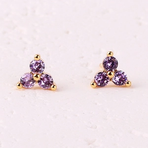 Three-petal flower stud earrings with purple zircons on a warm white stone base