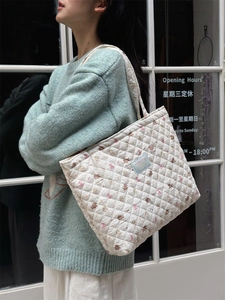 Detailed view of cream quilted tote bag with floral print and soft padded shoulder strap
