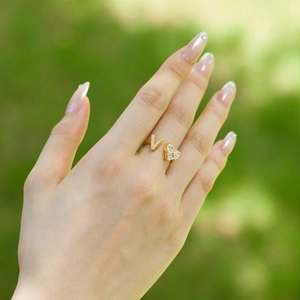 Detailed close-up of a gold S925 silver ring featuring a V-letter and heart zircon on a finger