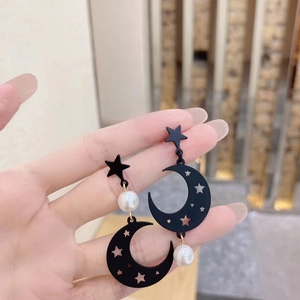 Detail of matte black moon and star earrings with elegant round white pearls