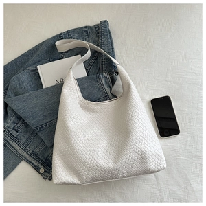 Flat lay of white woven leather bucket bag with a denim jacket and an art book