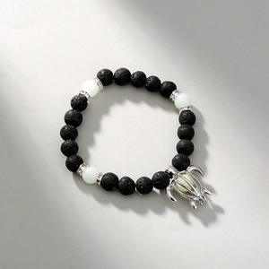 Detailed shot of black lava stone bracelet with luminous turtle pendant and silver accents