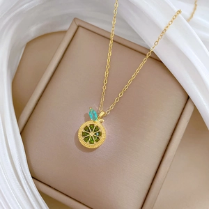 Macro shot of gold necklace with green lemon pendant featuring inlaid crystals