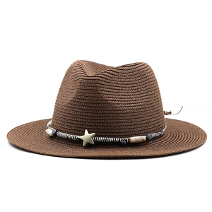 Detail of a brown straw fedora featuring a star charm and beaded decorative band