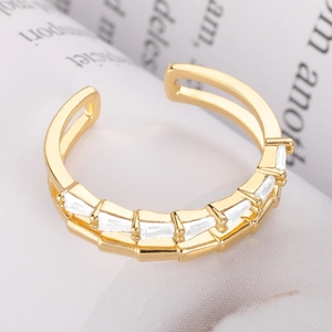 Adjustable gold ring with sparkling rectangular zircons on a white textured background