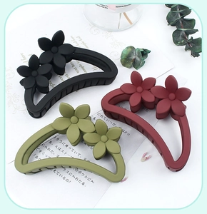 Detail of matte flower hair claws in black, burgundy, and olive green for elegant styling