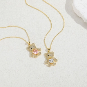 Macro detail of gold bear necklaces with pink and clear heart zircon pavé pendants