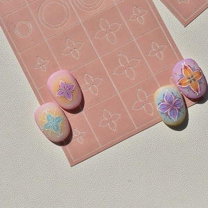 Autocollants ongles dégradés avec motifs floraux gaufrés sur un support rose doux