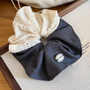 Détail d'un chouchou bleu-gris avec broderie en dentelle blanche et bouton décoratif