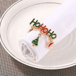 Golden HoHoHo Christmas napkin ring with Santa and tree charms on a white table setting