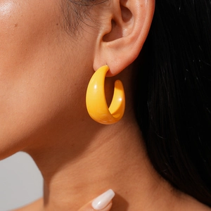 Polished yellow acrylic C-shape hoop earring worn by a model for a stylish look