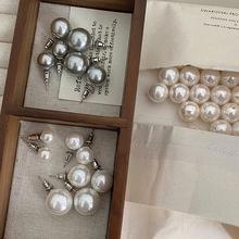 Macro shot of minimalist pearl earrings in grey and ivory white on a vintage wood box