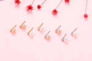 Detail of freshwater pearl stud earrings in gold and silver settings with crystals