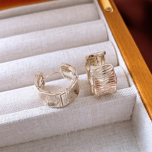 Macro shot of 18K gold plated huggie earrings with irregular textured crumpled finish