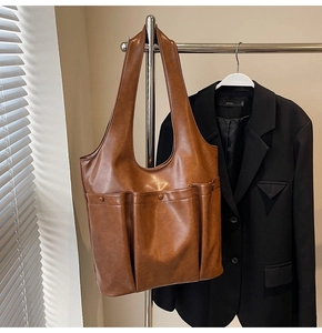 Detailed view of brown PU leather tote bag featuring two front pockets and wide strap