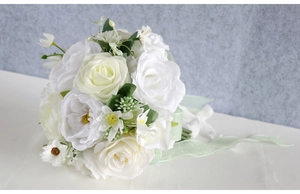 Detail of bridal bouquet with white roses, daisies and soft green organza ribbon